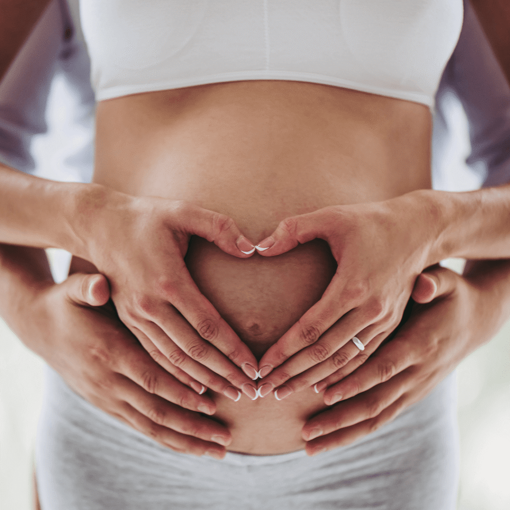 Pregnant woman with her and partner's hands on baby bump