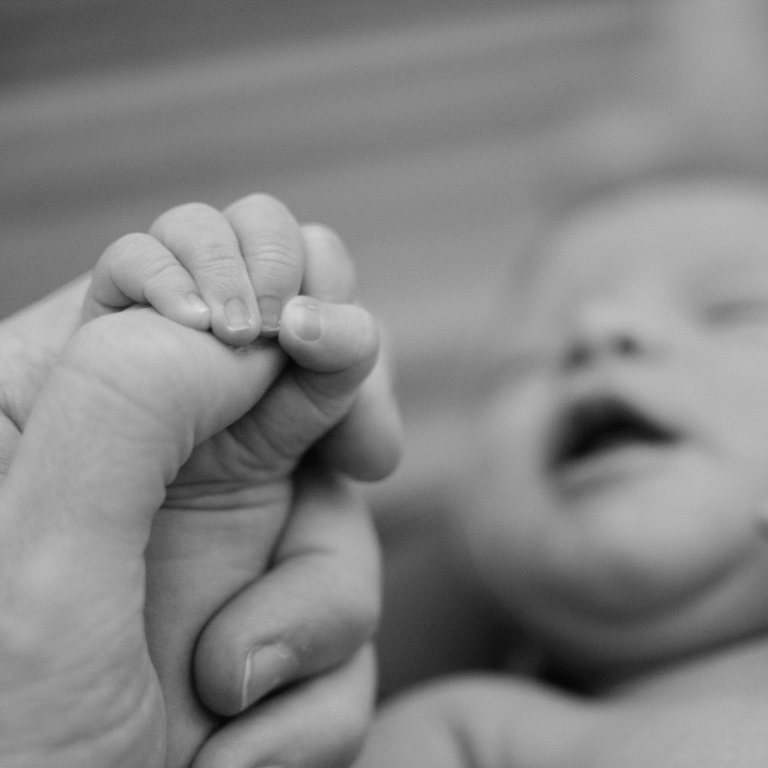 Newborn baby in black and white holding its foot