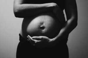 Black and white image of pregnant woman cradling baby bump.