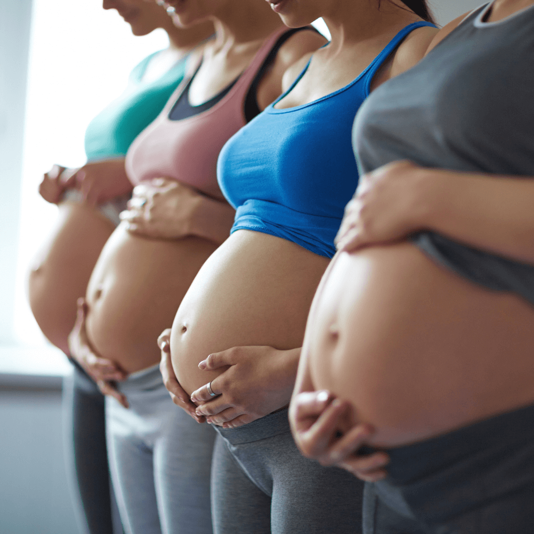 4 pregnant women caressing baby bumps