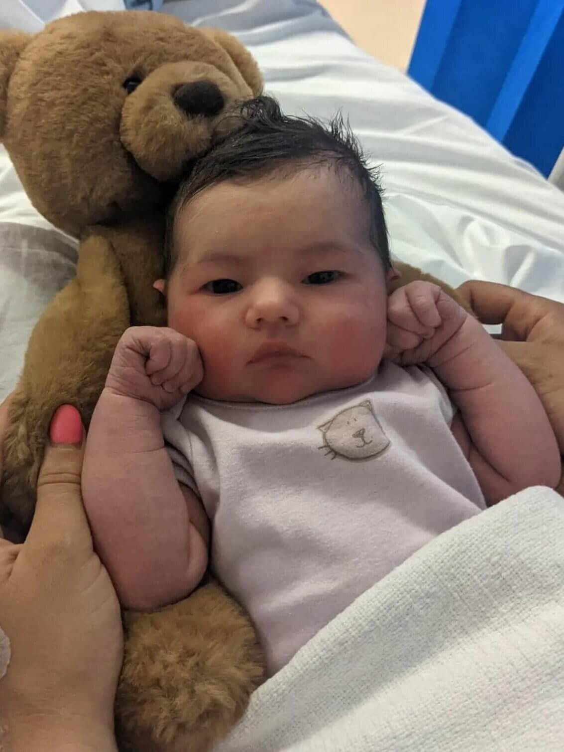 Newborn baby being cuddled by teddy bear