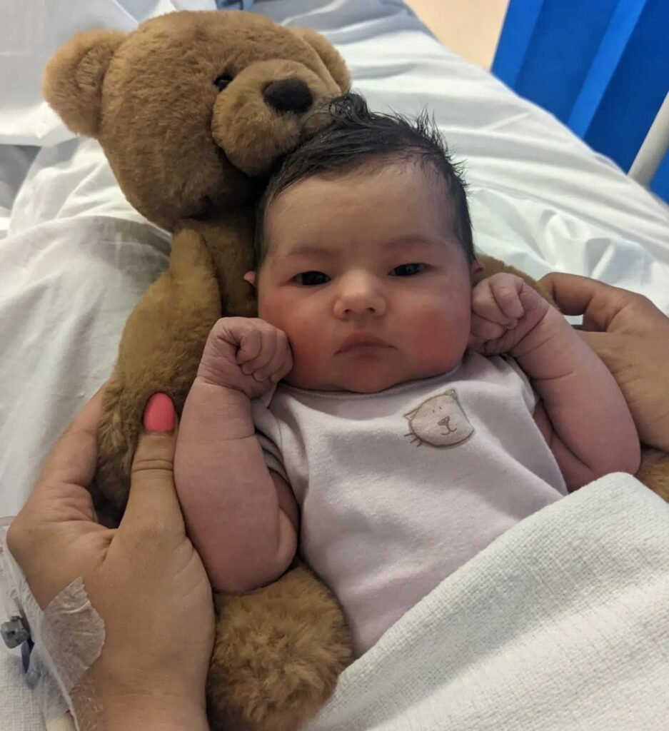 Newborn baby with teddy bear shortly after a positive caesarean birth.