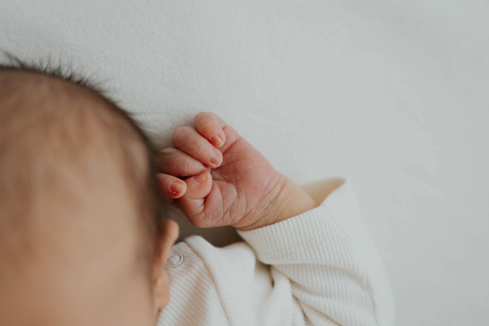 Head and hand of baby born to hypnobirthing mother in a gentle caesarean birth